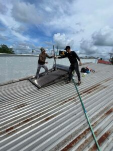 Nhân viên kỹ thuật lắp đặt máy nước nóng năng lượng mặt trời trên mái tôn